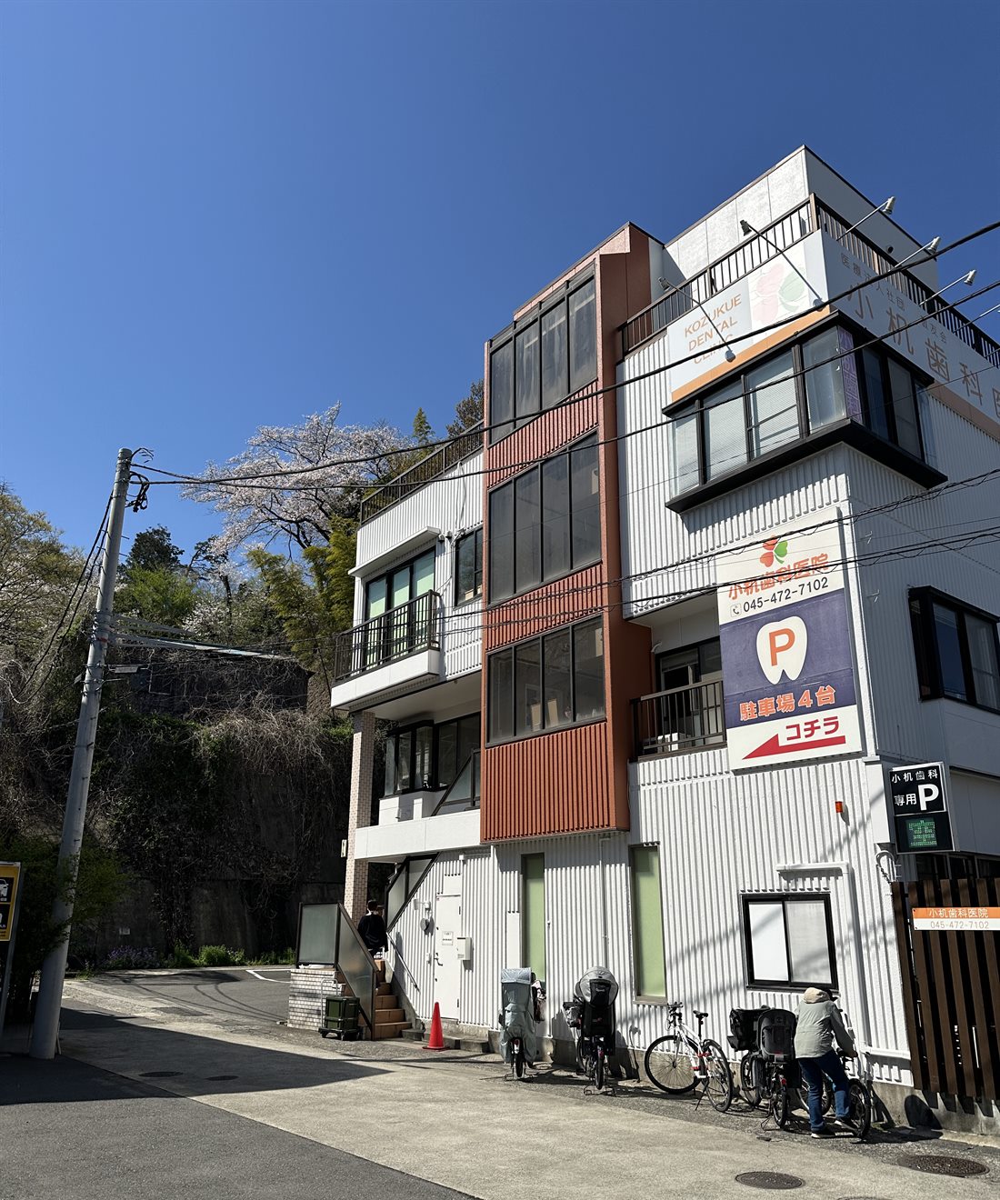小机歯科医院の外観。3階建ての建物に医院名の看板と「駐車場4台 コチラ」の案内が出ている